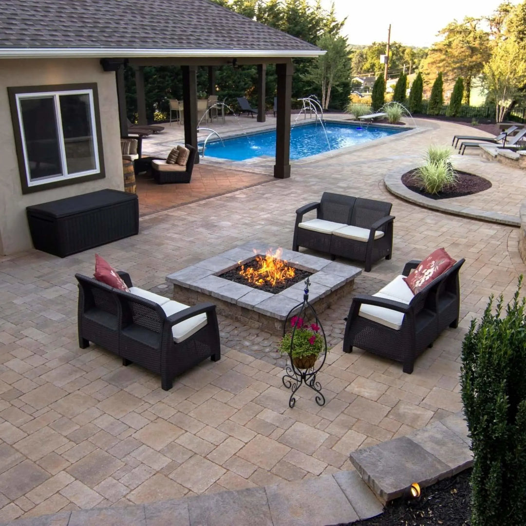 Cozy outdoor lounge setup featuring a lit square fire pit surrounded by wicker furniture and poolside elegance, showcasing the welcoming glow of an HPC square flat burner for family gatherings.