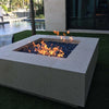 Contemporary backyard scene with a large limestone square fire pit filled with cobalt blue fire glass and dancing flames, powered by an HPC burner / perfect for upscale outdoor entertaining.