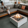 Sleek and contemporary patio with a white square fire pit filled with smooth black river stones, producing clean-burning flames from an HPC square flat burner, offering a cozy vibe in a stylish setting.