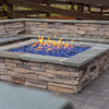 Built-in stone fire feature with vivid cobalt blue fire glass and bold yellow-orange flames, featuring HPC’s square flat burner technology / perfectly nestled into a wrap-around seating wall for social evenings.