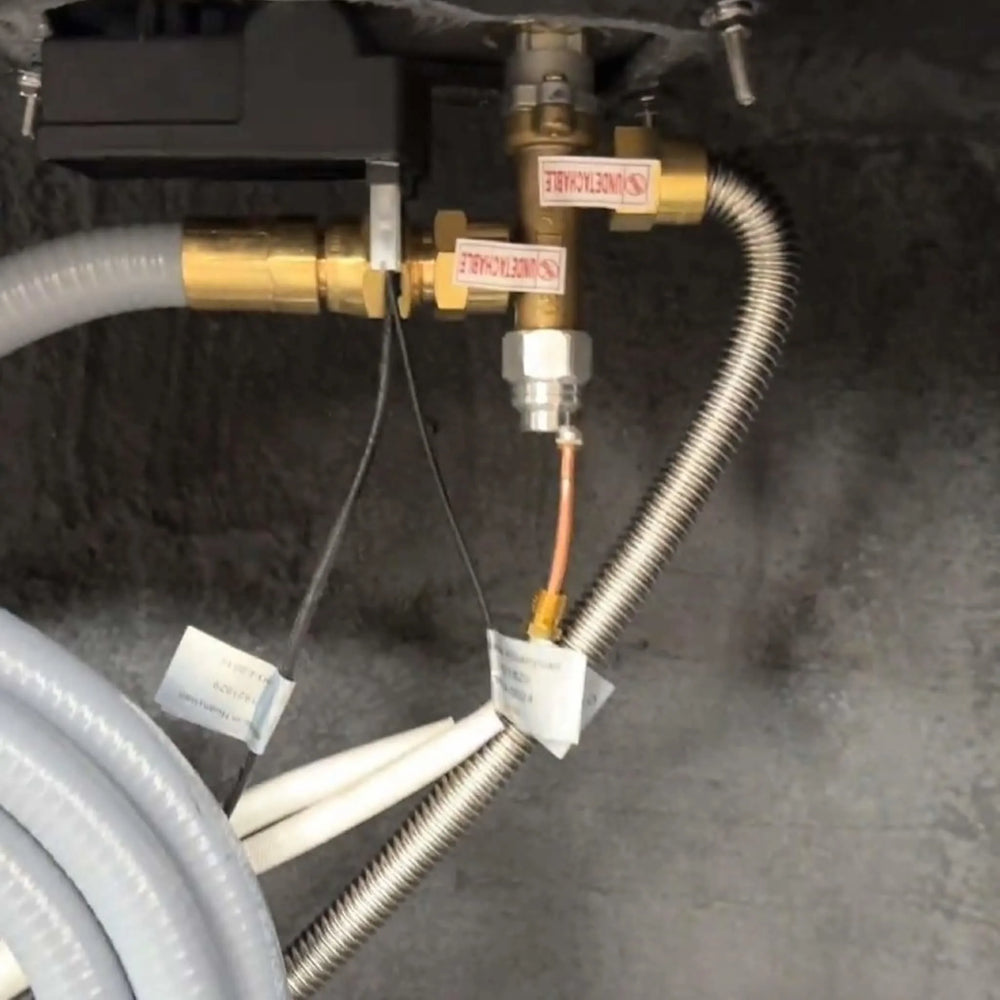 Installed Starfire Designs Béton Fire Pit Replacement Flex Line connected to gas components under the fire pit, demonstrating proper setup and secure fittings.