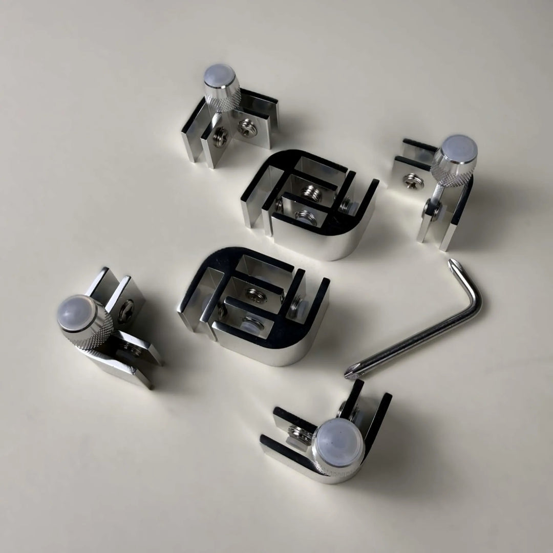 Top view of the Starfire Designs Béton Fire Pit Replacement Glass Wind Guard Clips Kit featuring precision-milled L-shaped clips, mounting hardware, and adjustment tools for rectangular or square guards.