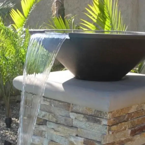Dark chocolate-finished Cazo water bowl with a wide spillway, pouring a sleek waterfall into a pool, blending modern style with soothing outdoor ambiance.