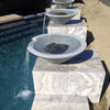 Modern limestone Cazo water bowls with smooth cascading streams flowing into a pool, creating a serene and elegant backyard water feature.