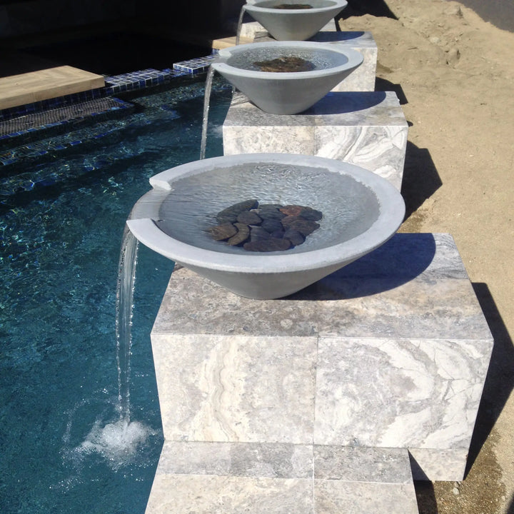 Modern limestone Cazo water bowls with smooth cascading streams flowing into a pool, creating a serene and elegant backyard water feature.