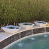 Three limestone Maya GFRC concrete water bowls with copper spillways, creating elegant waterfalls into a backyard pool for a modern and serene outdoor design.