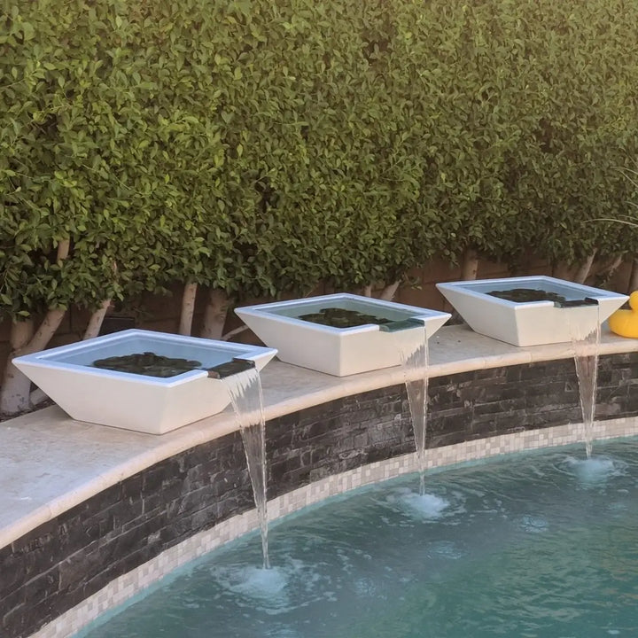 Three limestone Maya GFRC concrete water bowls with copper spillways, creating elegant waterfalls into a backyard pool for a modern and serene outdoor design.
