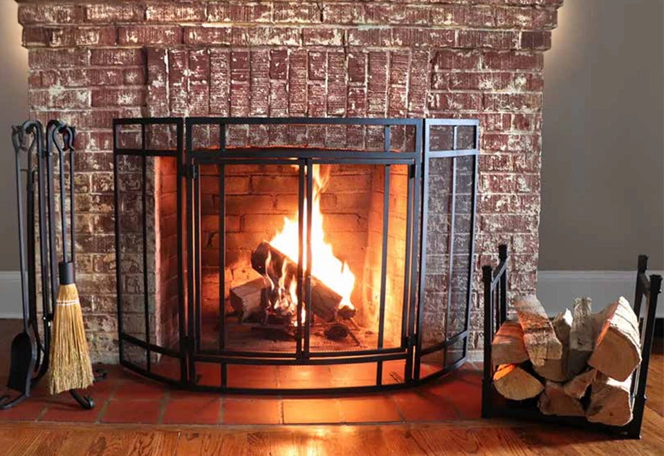 Cozy arched brick fireplace with a sturdy black metal screen door, showcasing natural wood-burning logs and vibrant flames for a classic, rustic ambiance.