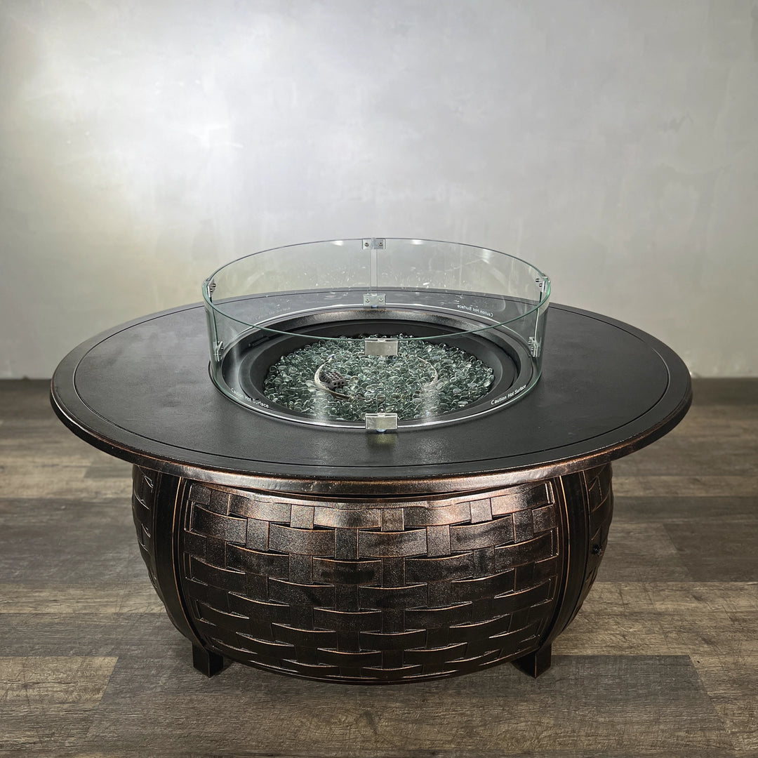 Golden Flame Bel Air 48” Oval Cast Aluminum Natural Gas Fire Table with glass wind guard and shimmering fire glass atop its oval surface, combining style and durability.