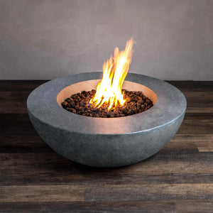 A side view of the Beton 42" Graphite Round Concrete Natural Gas Fire Pit featuring a modern, minimalist design with a push-button ignition system. The fire pit is filled with black lava rocks and has a smooth graphite finish that enhances its durability. Perfect for outdoor spaces, this natural gas fire pit offers warmth and elegance for a contemporary patio or backyard setting.