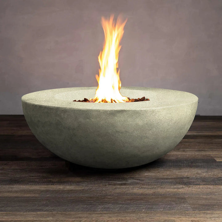 Beton 42-inch round concrete natural gas fire pit in sand color, with lava rocks and flames lit, featuring a push-button ignition for easy operation