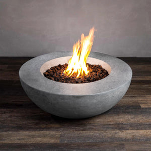 A natural gray, round concrete fire pit in a 42-inch size with a push-button ignition system, displayed at an angle with bright flames rising from the lava rocks. Ideal for outdoor use, this natural gas fire pit adds warmth and ambiance to any patio or backyard setting.