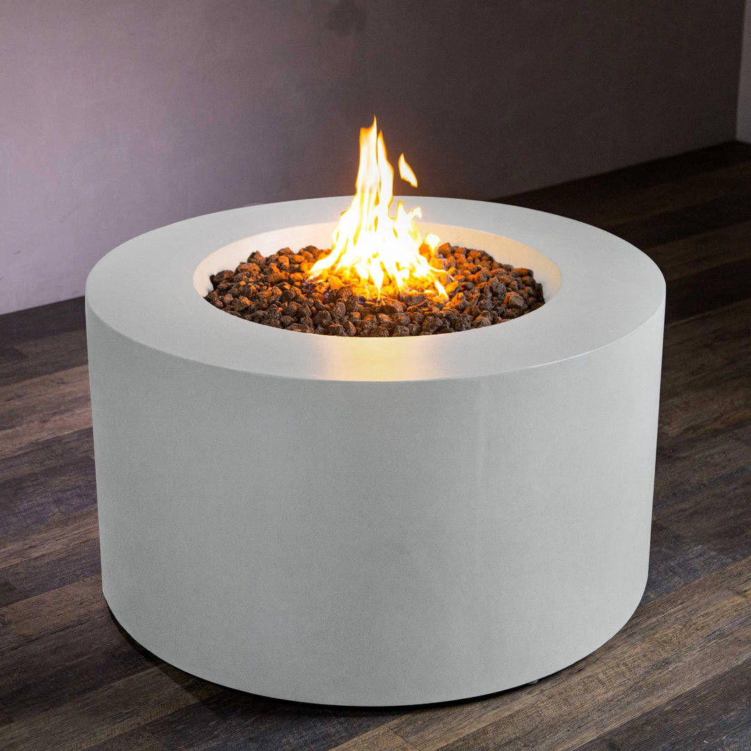 Front view of the Beton 42-inch white round concrete gas fire pit with access door, showcasing a smooth white concrete finish and a powerful flame emerging from the top. The fire pit is designed for natural gas and features lava rock for a clean, modern outdoor setup. Ideal for luxury outdoor spaces, the fire pit emphasizes durability and functionality