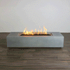A studio presentation highlights a rectangular concrete fire pit with a smooth grey finish, resting on a dark wood floor against a white wall. Yellow and orange flames flicker consistently along the length of the linear fire pit, rising from a bed of dark lava media. The minimalist setting emphasizes the clean lines and steady combustion of this modern fire pit, demonstrating the aesthetic appeal of a propane fire pit solution for contemporary spaces.