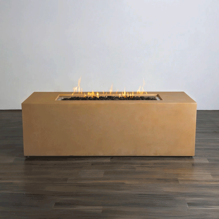 A studio view presents a rectangular concrete fire pit in a natural sand finish, resting on a dark wood floor against a white background. Bright orange flames rise continuously from a bed of black lava rocks along the length of the linear fire pit. The minimalist presentation emphasizes the smooth texture and steady flame height, demonstrating the clean operation of a natural gas fire pit connection.