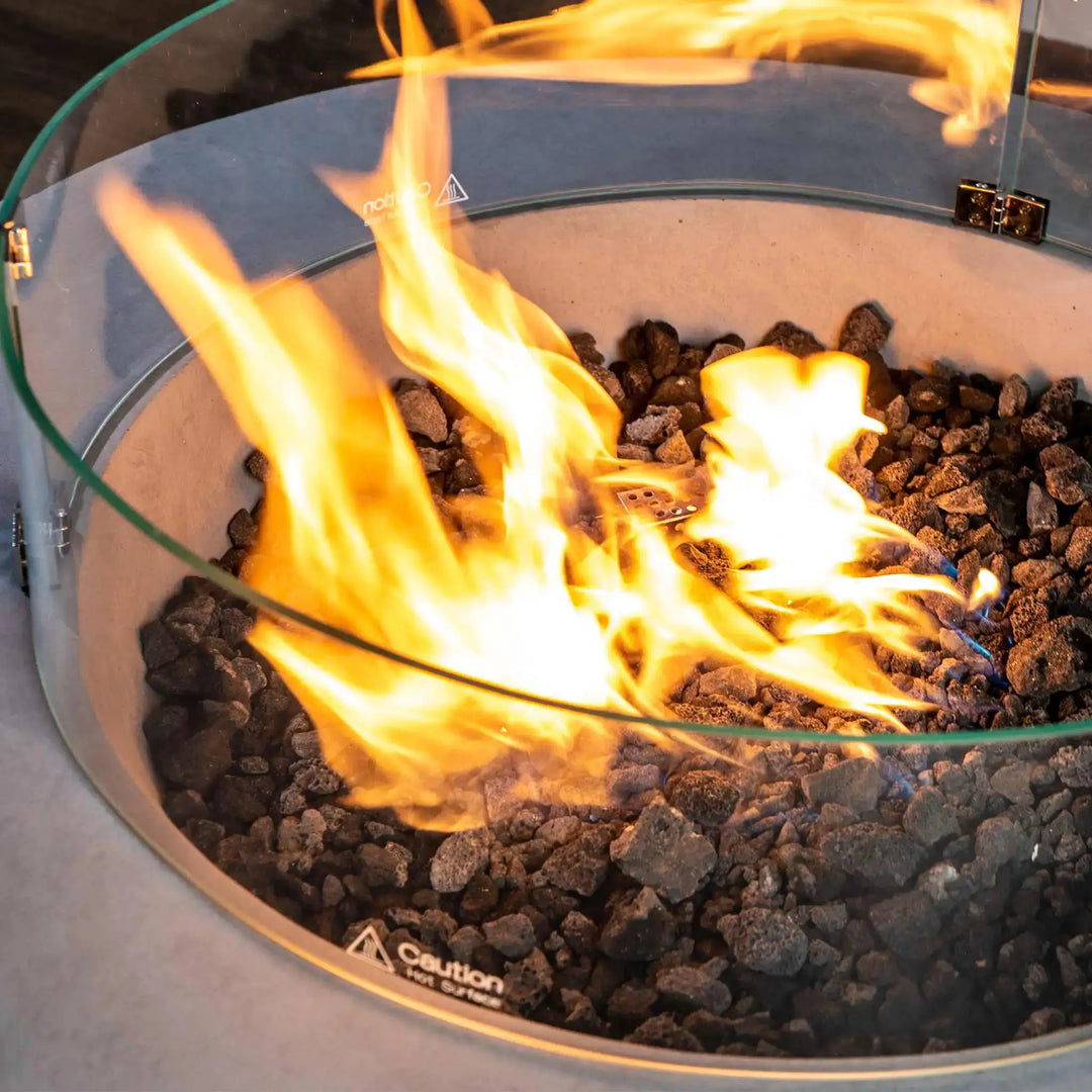 Closeup of the Starfire Designs Beton Round Glass Wind Guard with vibrant flames and lava rocks, enhancing fire pit safety and aesthetics