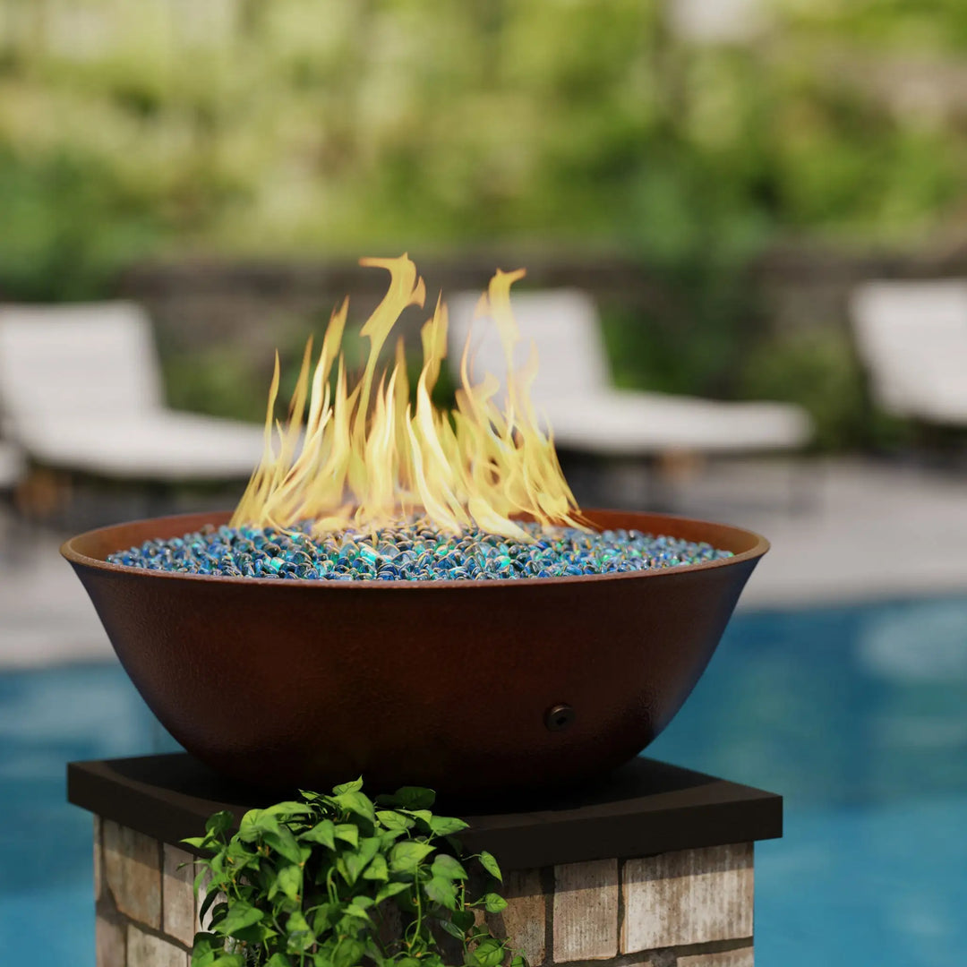 Campana Moreno 31-inch copper fire bowl by Starfire Designs, displayed poolside with vibrant blue fire glass and dancing flames, perfect for a luxury outdoor setting