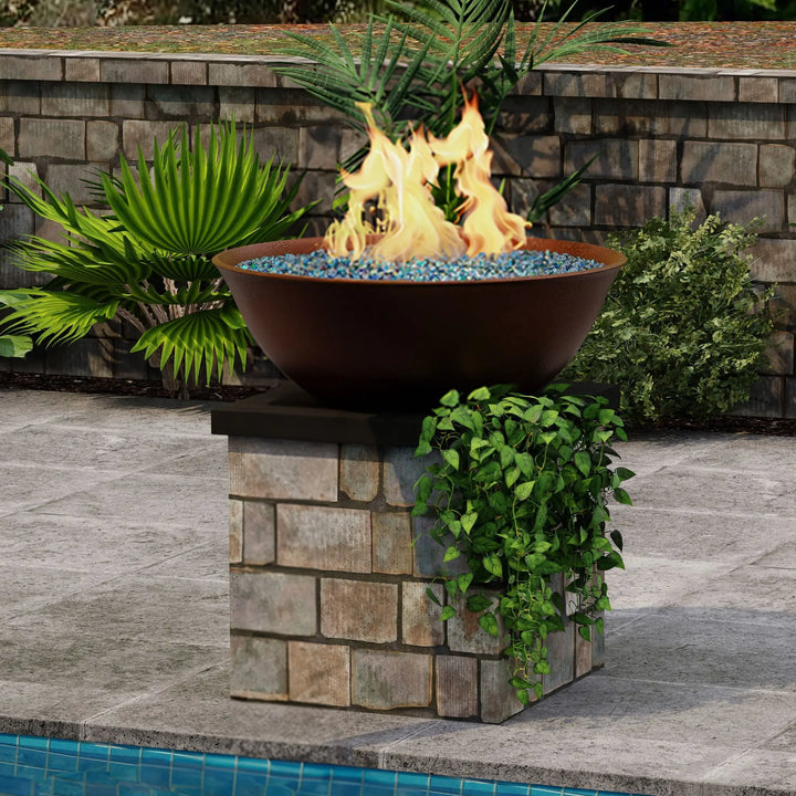 Campana Moreno 31-inch round copper fire bowl by Starfire Designs, showcased on a stone pedestal beside a pool with blue fire glass and vibrant flames, enhancing the luxury outdoor patio area