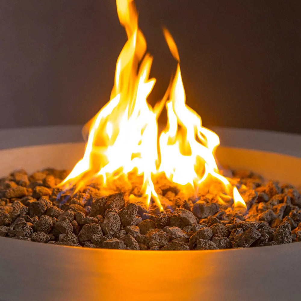 Close-up view of the vibrant flames on the Starfire Designs Beton 42" round propane tank gas fire pit in natural gray, highlighting the realistic lava rocks and the sleek modern edge of the fire pit bowl