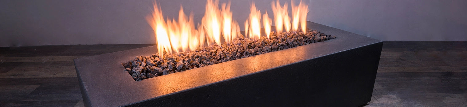 Sleek modern rectangular fire pit filled with dark lava rocks, featuring flames rising from the center, perfect for creating a warm and inviting ambiance in contemporary indoor or outdoor spaces.