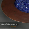 Close-up of the hand-hammered copper rim of the Cono Moreno 42-inch Round Copper Fire Pit, showcasing the detailed craftsmanship with blue fire glass