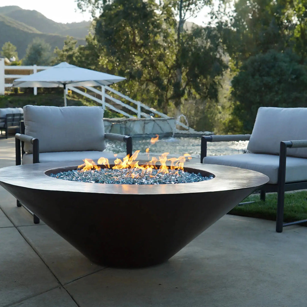 Cono Moreno 42-inch Round Copper Fire Pit on a modern patio, showcasing a sleek hand-hammered copper finish with shimmering blue fire glass, perfect for outdoor gatherings and enhancing backyard spaces