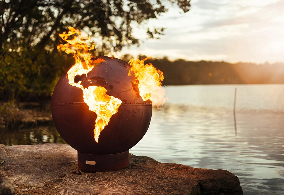 Unique earth globe metal fire pit with cut-out continents, showcasing vibrant flames in a round outdoor fire bowl design. Ideal for modern backyard fire pit settings.