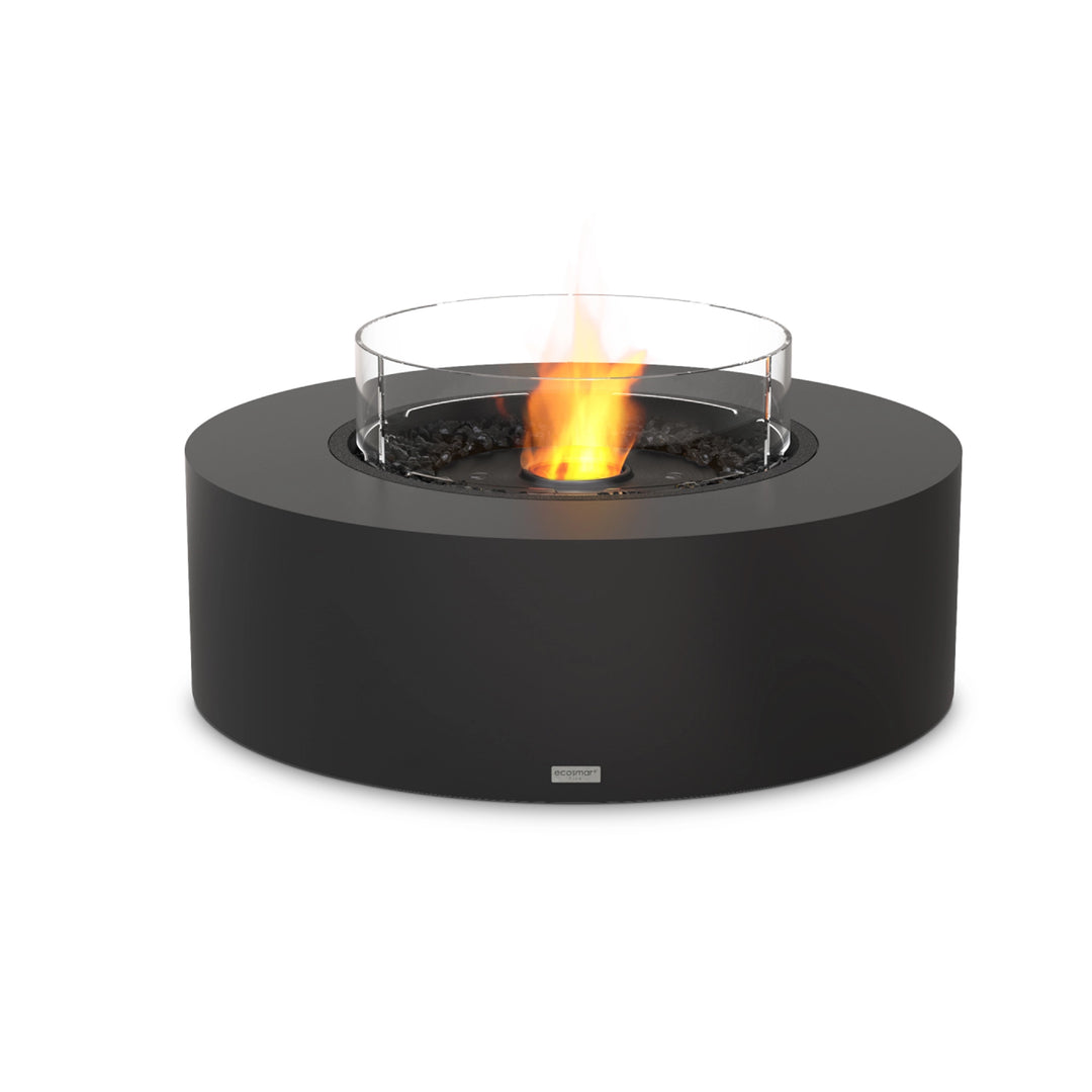 The EcoSmart Fire Ark 40 in graphite finish, featuring a black ethanol burner with a protective glass wind guard. This modern outdoor fire pit has a sleek cylindrical design, built with durable concrete composite. The fire pit is filled with black fire media, enhancing the vibrant eco-friendly ethanol flame. Ideal for luxury patio heating, backyard ambiance, and modern outdoor spaces.

