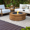 The EcoSmart Fire Ark 40 Teak round fire pit is set on a stylish outdoor deck with woven furniture and a cozy ambiance. Made from premium teak wood, this luxury fire feature includes a stainless steel burner and black fire glass, providing a warm glow. A perfect addition to modern patios, backyards, and fire pit tables, ideal for entertaining guests in an elegant outdoor lounge.