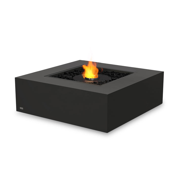 EcoSmart Fire Base 40 Graphite with ethanol black burner and a protective glass wind guard. The transparent windscreen enhances safety while allowing an unobstructed view of the flames. This square gas fire pit features a sleek, dark concrete body and black fire media, perfect for luxury outdoor spaces.