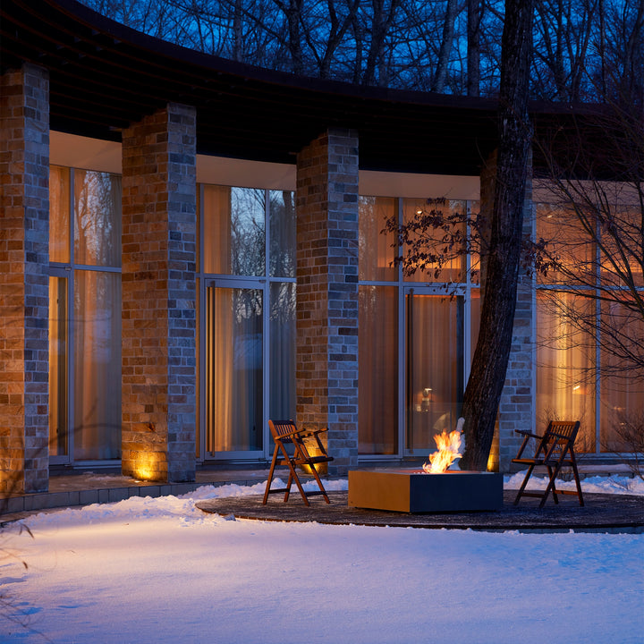 A breathtaking EcoSmart Fire Base 40 fire pit glowing against a snowy backdrop in a winter setting. The freestanding fire pit radiates warmth, making it an ideal outdoor fire bowl for all-season use. Its contemporary design makes it a standout fire pit for the backyard or luxury outdoor spaces.

