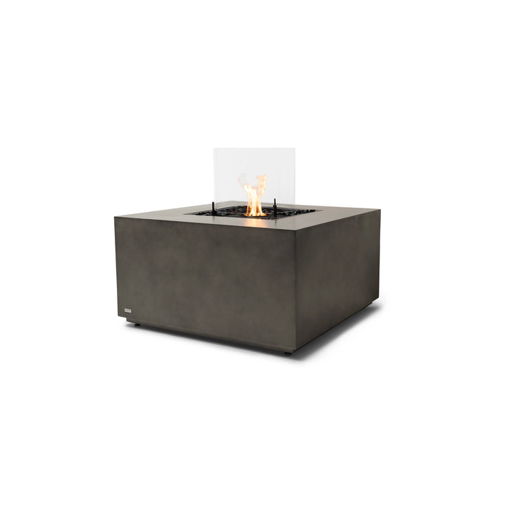 A stunning EcoSmart Fire Chaser 38 Natural outdoor gas fire pit with a black burner and a protective glass wind guard. Its natural-colored concrete base provides a neutral yet stylish look, while the natural gas or propane burner ensures clean and efficient flames for outdoor relaxation.