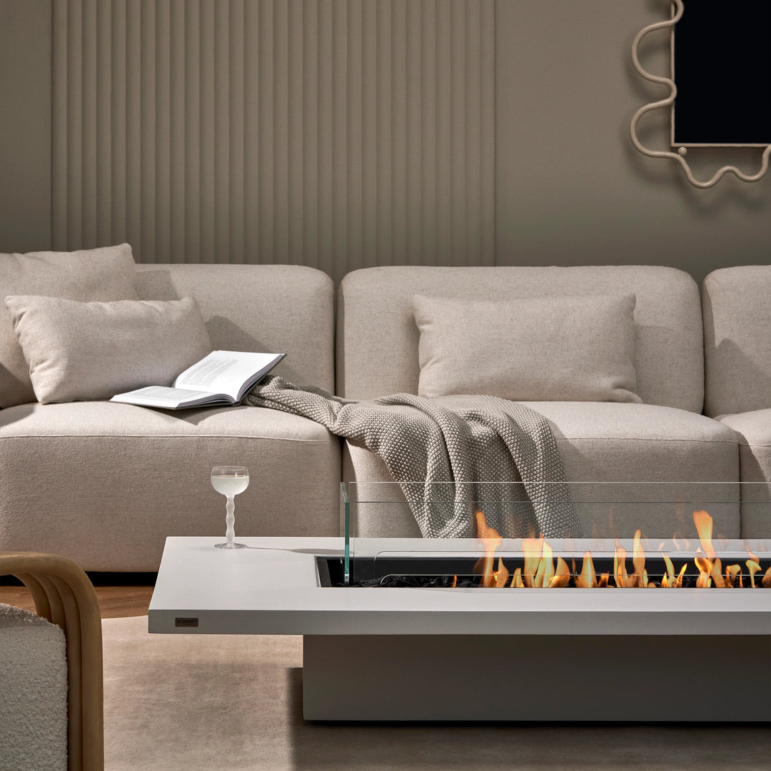 The EcoSmart Fire Daiquiri 70 set in a luxurious indoor lounge with a modern sectional sofa. A fire pit table that enhances both indoor and outdoor fire pits aesthetics.