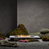 The EcoSmart Fire Daiquiri 70 in an elegant garden setting with moss and stone elements. A natural gas fire pit perfect for modern outdoor fire pits.