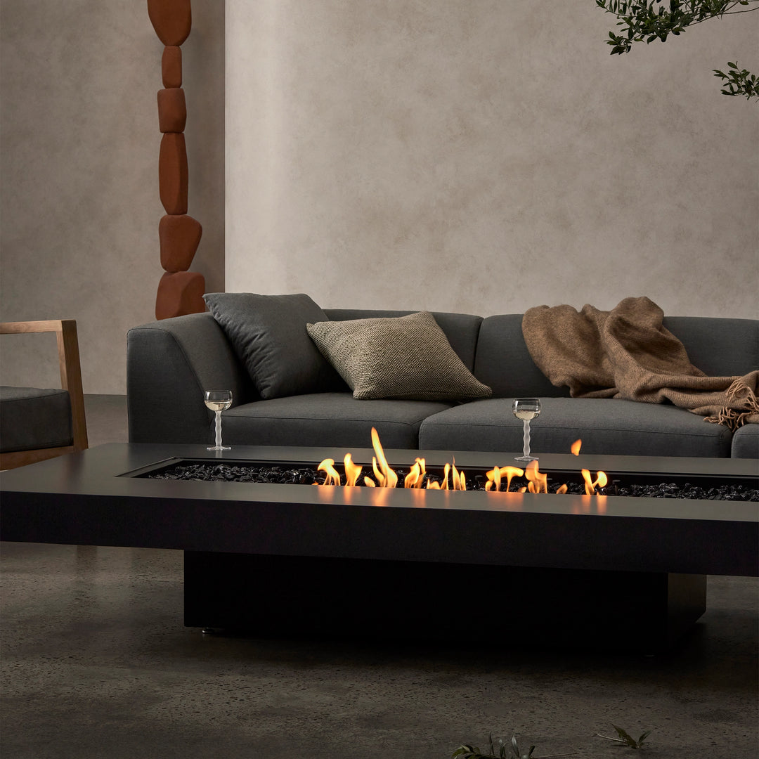 A close-up of the EcoSmart Fire Gin 90 (Low) fire table, showcasing its realistic flames dancing over black fire media. The sleek and modern design makes this indoor fire pit a perfect fire table for contemporary living rooms. Its long burner and minimalistic styling elevate any space with a sophisticated and warm ambiance.