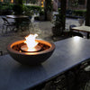 The EcoSmart Fire Mix 600 Natural Fire Pit is beautifully displayed on a marble-top dining table, creating a cozy and sophisticated outdoor fire table ambiance. Its bioethanol flame flickers against the smooth stone surface, making it a versatile fire pit for outdoors. The round fire pit with natural concrete finish provides warmth and style for any modern outdoor fire pit setting.