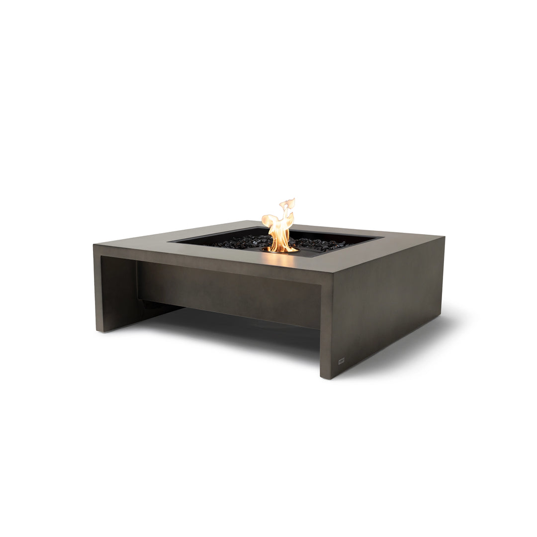 The EcoSmart Fire Mojito 40 Natural outdoor fire pit features a sophisticated square design with a sturdy concrete base in a natural earth-tone finish. It is fitted with a black burner pan, seamlessly integrating into the modern aesthetic. The fire pit is powered by natural gas or liquid propane, providing clean-burning flames over a bed of black fire glass. This luxury fire feature is perfect for backyard entertaining, patios, and outdoor lounges, offering both warmth and a striking visual appeal.