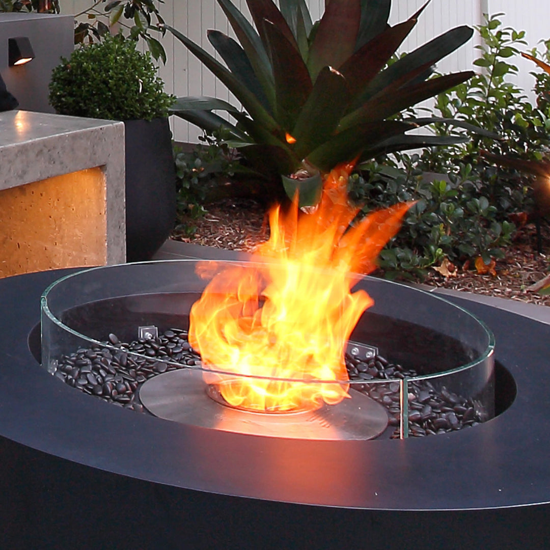 The EcoSmart Fire R530 Fire Screen installed on a stylish black outdoor fire pit, featuring vibrant flames and black fire rocks. This wind guard offers enhanced flame stability, making it a must-have fire pit accessory for contemporary patios and outdoor entertaining spaces.