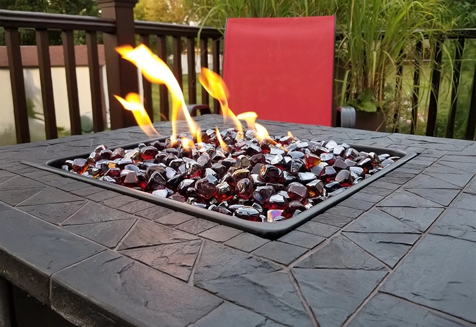 Modern gas fire pit with sparkling fire diamonds glass, featuring rich red and silver tones, set in a stylish stone tabletop on a cozy outdoor patio.