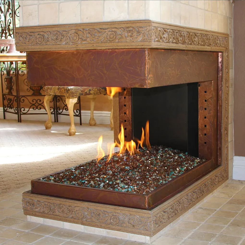 Luxury corner fireplace with intricate decorative trim, filled with brown fire glass and emitting flames, situated in an elegant room with warm tones and classic furniture