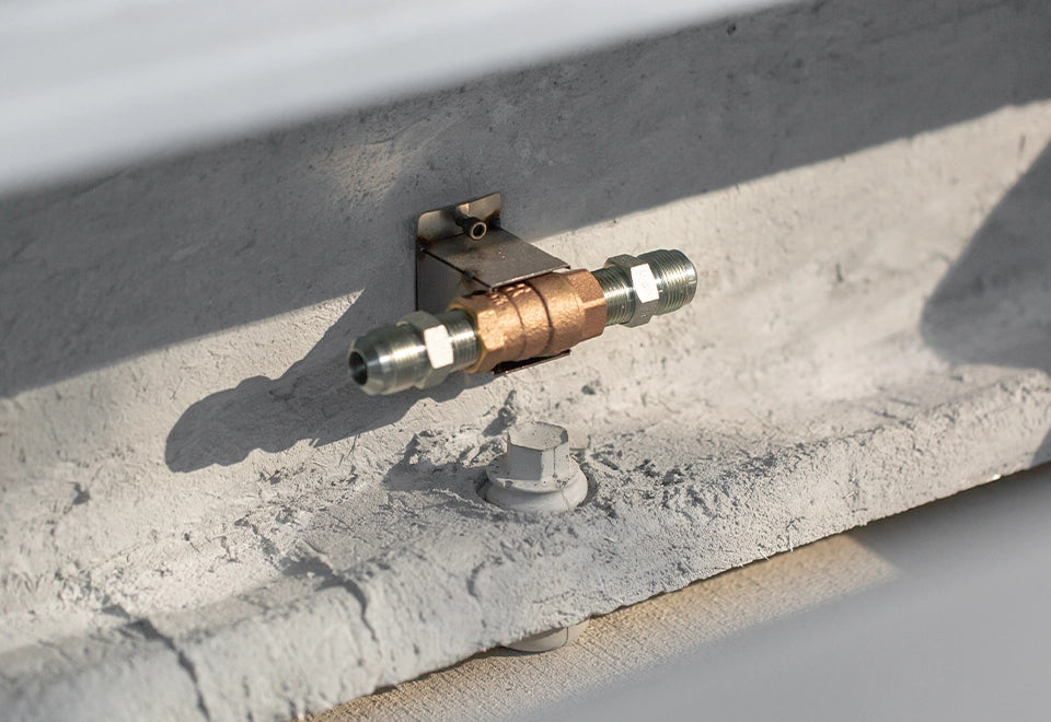 Close-up of a fire pit key valve gas connection, securely mounted on a concrete surface for controlled flame adjustment.