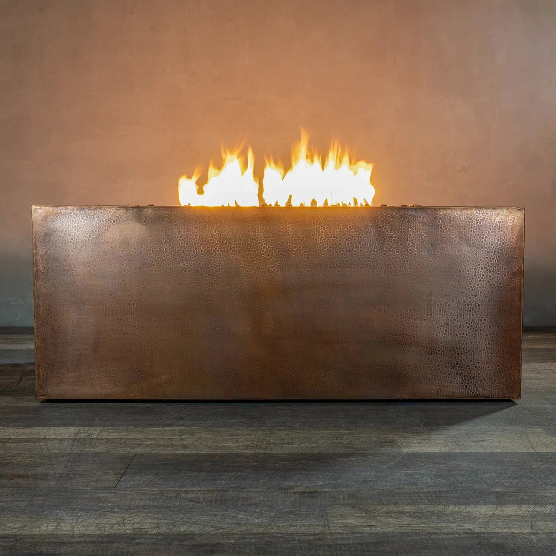 Side view of the Gravity Moreno 60x32 rectangular copper fire pit by Starfire Designs, featuring a sleek and rustic copper finish with flames emerging from the linear burner, ideal for elegant outdoor spaces