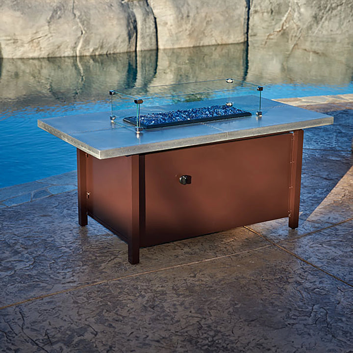 Linear Glass Flame Guard by American Fireglass shown in a sleek, modern fire table setup by the poolside. The wind guard is constructed from durable tempered glass, offering a functional solution to protect fire pit flames from wind while enhancing the fire table's aesthetic. Perfect for any outdoor space looking to combine safety and elegance, especially near water features or outdoor entertainment areas. Complements contemporary fire tables and provides a crystal-clear view of the flames