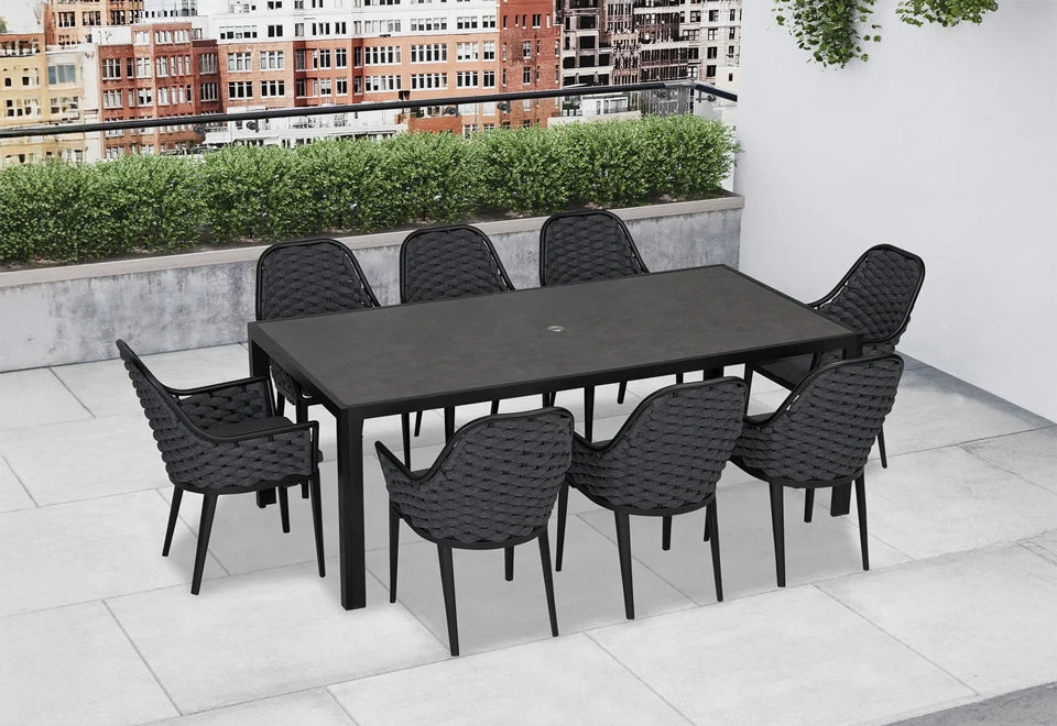 Stylish black outdoor dining set featuring a sleek rectangular table and eight woven dining chairs on a modern rooftop patio with city views.