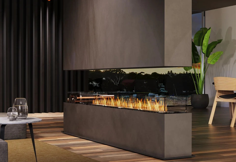 Luxury three-sided gas fireplace with a sleek glass enclosure, set in a modern living space with a panoramic waterfront view.