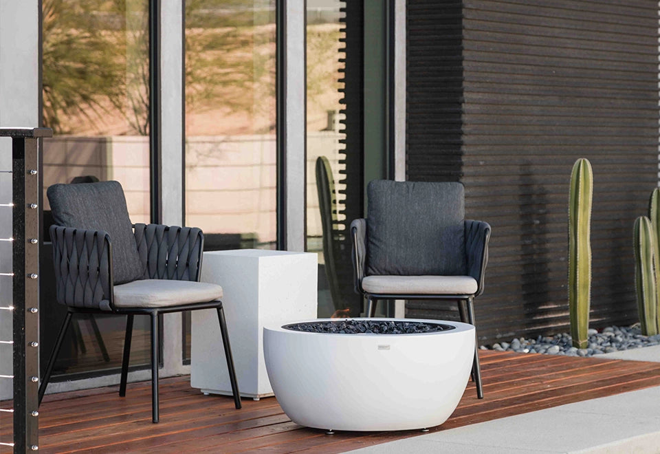 Chic modern white round outdoor fire bowl with smooth concrete finish and black fire glass, ideal as a patio fire pit for contemporary backyard settings.