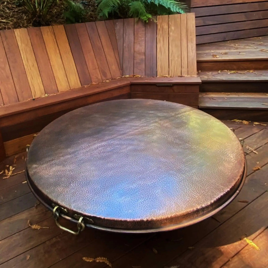 This image showcases the intricate hammered texture of the Moreno 48" Round Copper Fire Pit Lid by Starfire Designs. The hand-hammered copper finish highlights the unique, rustic beauty of this durable lid, which is specifically designed to protect your fire pit. Each lid is one-of-a-kind with slight variations in texture. Keywords: 48-inch round copper fire pit lid, Moreno copper fire pit lid, hand-hammered copper, rustic copper fire pit lid, outdoor fire pit accessories.