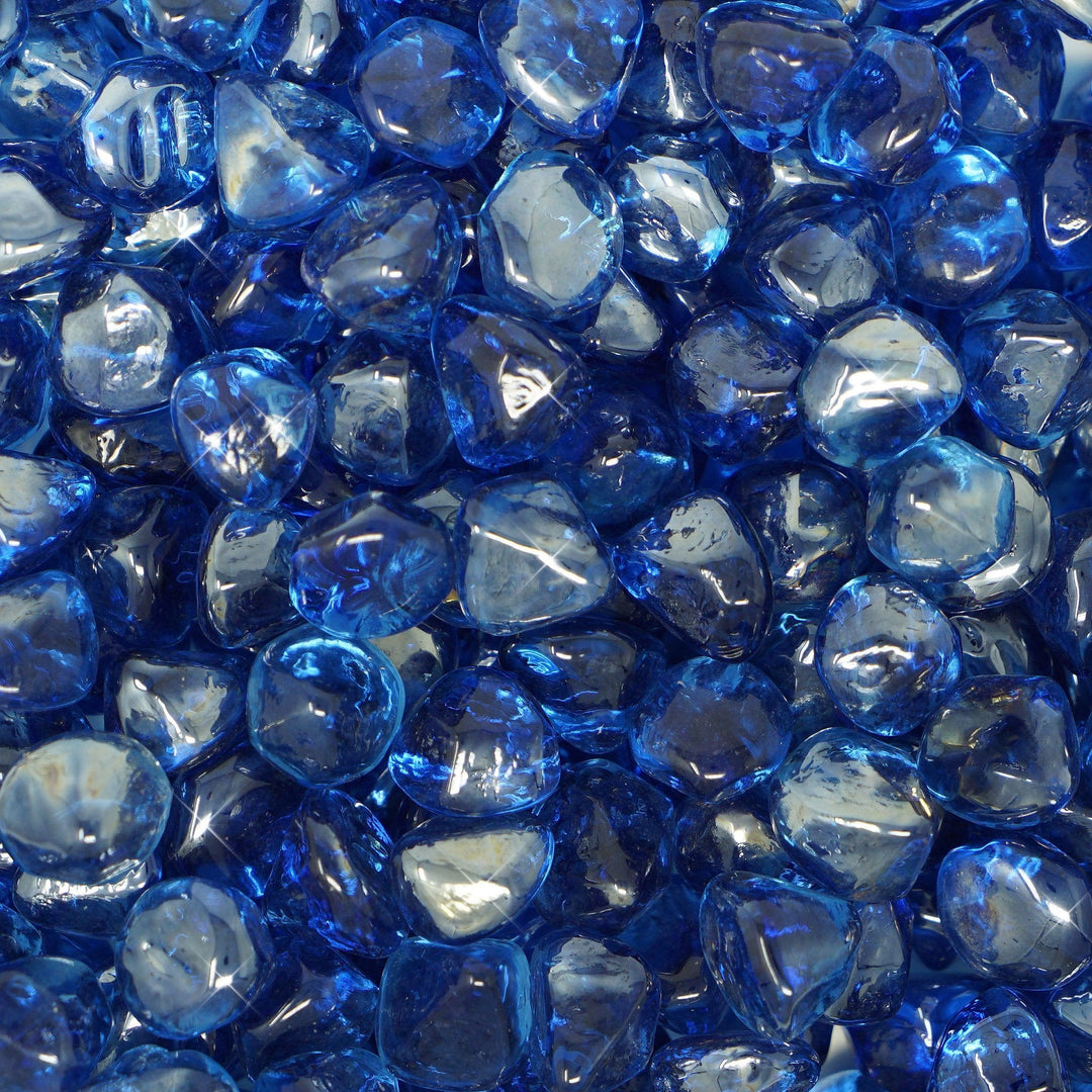 Close-up view of Mr. Patio Fire Glass Fire-Diamonds in deep blue. The glass pieces are reflective and faceted, creating a dazzling visual effect when flames are present. Perfect for enhancing outdoor fire pits, the vibrant blue fire glass adds a luxurious touch and radiates elegance. Ideal for outdoor fire pits, fireplaces, and gas fire tables, these fire diamonds are crafted to withstand high temperatures, making them a durable and decorative choice for any modern fire feature