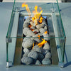 Starfire Designs outdoor rolled lava rocks arranged in a rectangular fire pit, with a glass guard surrounding the flames. These durable lava rocks, available in sizes from 1 to 5 inches, provide a visually appealing and heat-efficient medium for fire features, creating a warm and inviting atmosphere in any outdoor space