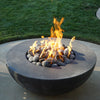 A nighttime view of a fire pit filled with Starfire Designs rolled lava rocks, showcasing their heat retention capabilities as flames rise from the center. The large lava rocks (3-5 inches) create a natural and rustic look, ideal for outdoor fire features in both residential and commercial settings